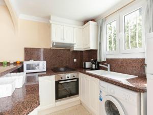 a kitchen with white cabinets and a washer and dryer at Apartment Club Sevilla I-3 by Interhome in Casas Devesa