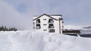 ホレズにあるPensiunea Varful Romanのスキー場横の雪に覆われた建物