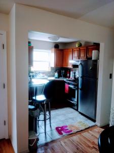 a kitchen with a black refrigerator and a table at Pleasant Place Rooms in Queens