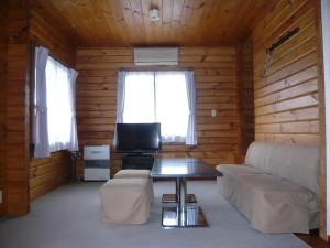 a living room with a couch and a table at Hakuba Happo Log Chalets in Hakuba