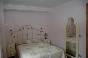 Habitación blanca con cama y espejo en Apartamentos Torremar, en Isla