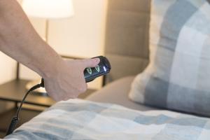 a person holding a remote control next to a bed at Harzer-Bachtaeler in Benneckenstein