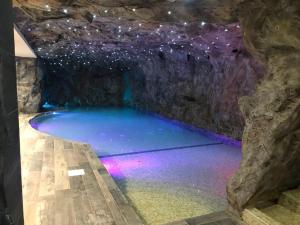 a pool of water in a cave with purple lights at National Park Hotel & Spa in Cotronei