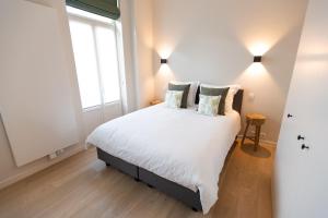 Un dormitorio con una gran cama blanca con almohadas. en Blossom & Bloom, en Brujas