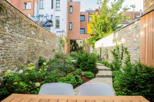 un jardín con mesa de madera y sillas blancas en Blossom & Bloom, en Brujas
