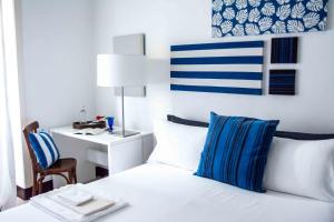 a white bed with blue and white pillows and a desk at Fuoridalguscio Home in Leuca