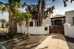 a house with palm trees and a fence at Villa Bella Lanzarote in Costa Teguise