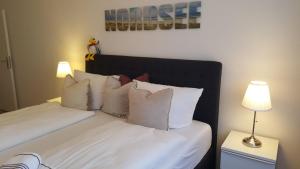 App-Syltliebe-Haus-Ankerlicht-Whg-70 في فيسترلاند: غرفة نوم بسرير ذو شراشف ووسائد بيضاء