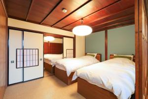 een kamer met 2 bedden en een deur naar een slaapkamer bij Higashiyama Chitaru in Kanazawa in Kanazawa