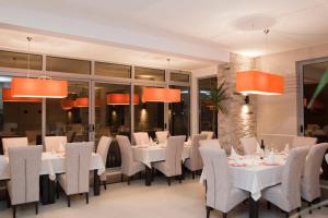 een restaurant met witte tafels en stoelen en oranje verlichting bij Hotel Laguna in Ulcinj