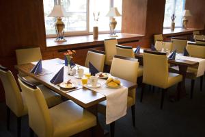 Hotel Marttel في كارلوفي فاري: مطعم بطاولات خشبية وكراسي صفراء