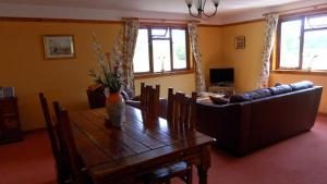 a living room with a wooden table and a couch at Meadowside Cottages in Balavil