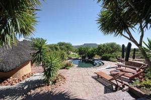 un patio trasero con una piscina con bancos y árboles en Waterberg Guest Farm, en Waterberg