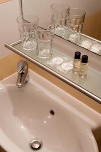 a bathroom sink with glasses on a shelf above it at B&B Miracolo di Mare Retro in Piran