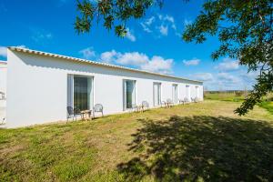 a white building with chairs on a grass field at Monte Da Azarujinha in Azaruja