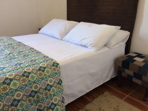 a bed with white sheets and a quilt on it at Praça Residence in Uruguaiana