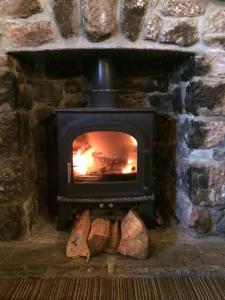 a stone fireplace with a fire in it at King's Head Inn in Llangennith