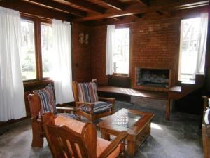 a living room with a fireplace and chairs and a table at Cabañas Casa Loló in Mar de las Pampas
