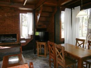 a dining room with a wooden table and a television at Cabañas Casa Loló in Mar de las Pampas