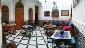 Habitación con suelo de baldosa, mesas y sillas. en Dar Hayati, en Fez