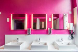 a bathroom with two sinks and two mirrors at Safestay London Kensington Holland Park in London