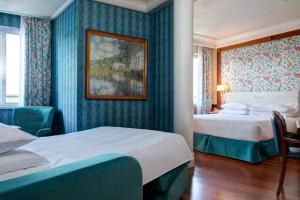 a hotel room with two beds and a painting on the wall at Hotel Capitol Milano in Milan +43 photos