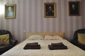 リヴィウにあるApartments in Lviv centerのベッドルーム1室(ベッド1台、椅子2脚、ポートレート2枚付)