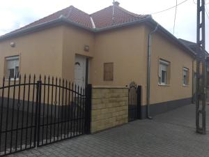 Zsike vendégház في Tolna: منزل به سياج اسود وبوابة
