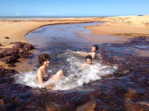 três meninos brincando na água na praia em Arte Vida Hostel em Itaúnas