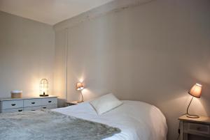 CauxにあるGite de Mougeresのベッドルーム1室(白いベッド1台、テーブルにランプ2つ付)