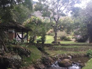 a garden with a stream and a cabin at Sitio Recanto Lumiar in Nova Friburgo