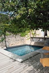 - une petite piscine sur une terrasse en bois avec une table dans l'établissement Gite de Mougeres, à Caux