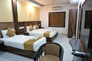 a hotel room with two beds and a chair at Hotel Kochi Crown in Cochin