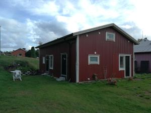 a red barn with a white cow in a yard at Lin's B&B in Älvsered