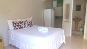 - une chambre avec un lit blanc et un réfrigérateur dans l'établissement Pousada Encanto Das Aguas, à Lindóia