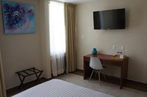 1 dormitorio con escritorio y TV en la pared en Hotel Mirante Tlaxcala en Tlaxcala de Xicohténcatl