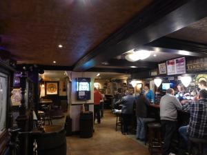 a group of people standing around a bar in a pub at Corran House Guest House in Oban