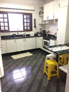 una cocina con armarios blancos y taburetes amarillos en Casa Da Tiete - Foz do Iguaçu - PR, en Foz do Iguaçu
