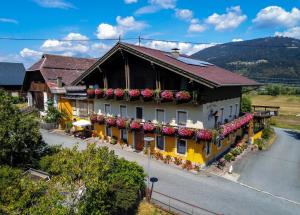 un edificio giallo e bianco con sopra dei fiori di Hotel Beim Winkler a Tröpolach