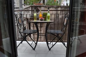 einen Tisch mit 2 Stühlen und Flaschen Wein auf dem Balkon in der Unterkunft Chez Amélie & Jean-Louis in Catania