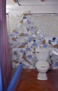 a white toilet sitting next to a bathroom wall at Hostel La Ballena Backpacker in Las Galeras