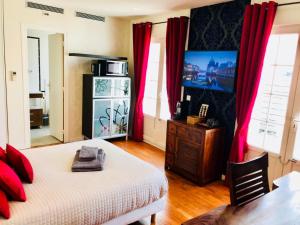 a bedroom with a bed with red curtains and a television at Villa Florian in Neuilly-Plaisance