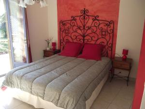 a bedroom with a large bed with red pillows at Domaine des cigales, chambre d'hôtes in Saint-Martin-dʼAoût