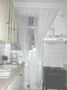 - une cuisine avec un rideau sur un évier et une cuisinière dans l'établissement Αnna's Home!!!Holidays in beautiful Athens, à Athènes