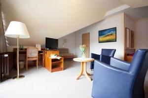 a living room with a couch and a table with a tv at PP- Hotel Grefrather Hof in Grefrath