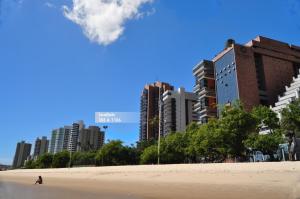 a person walking on the beach in front of buildings at Seaflats Iracema Residence in Fortaleza