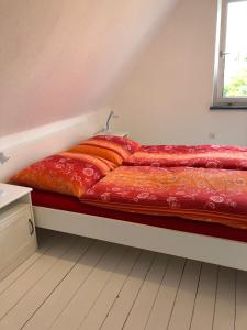 レーアにあるFerienhaus an der Evenburgの赤いシーツと窓が備わるドミトリールームのベッド1台分です。