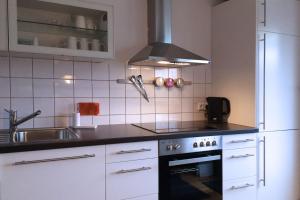 a kitchen with white cabinets and a stove top oven at Fabys Ferienwohnung in Twielenfleth