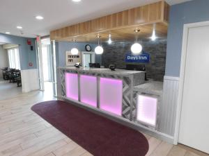 a lobby with a bar with pink lighting at Days Inn by Wyndham West Des Moines - Clive in Clive