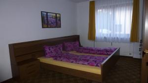 a bedroom with a bed with purple sheets and a window at Apartement Hasenauer in Fieberbrunn